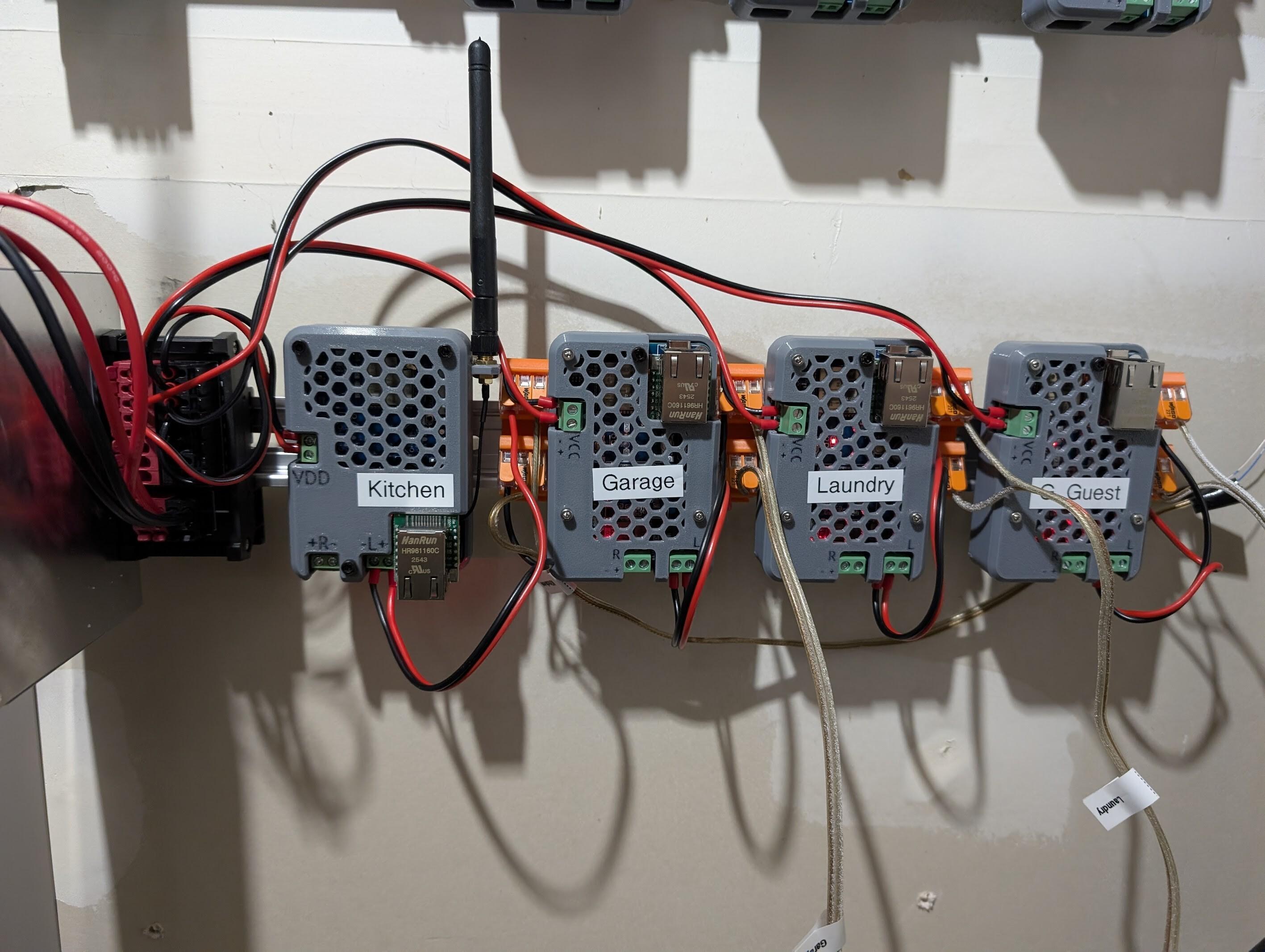 Louder-ESP32s, in 3D printed cases, mounted on a DIN rail, wired into speakers and power